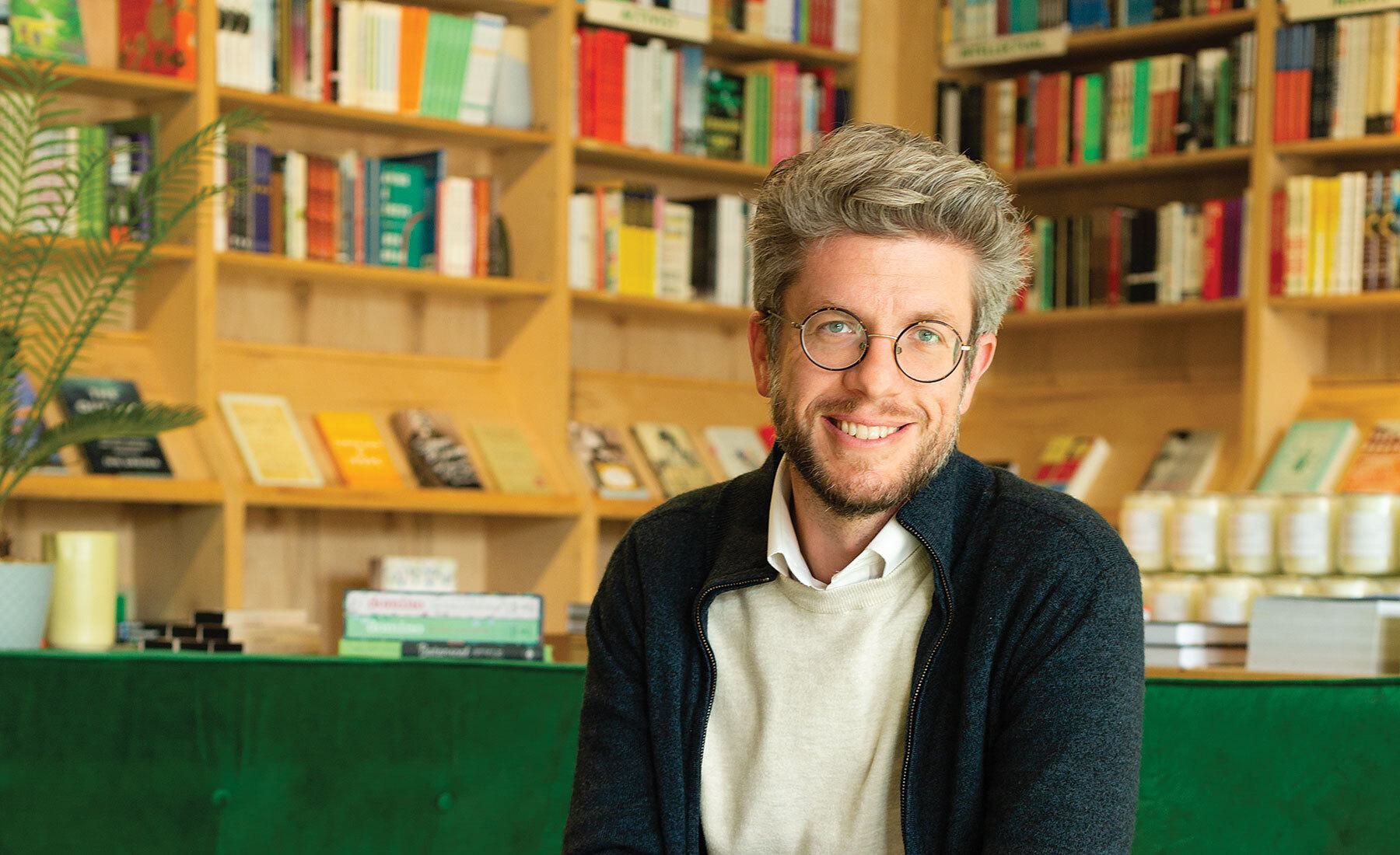 Man smiling in front of books in bookcases