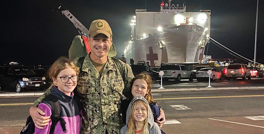 Family embraces in front of Navy hospital ship