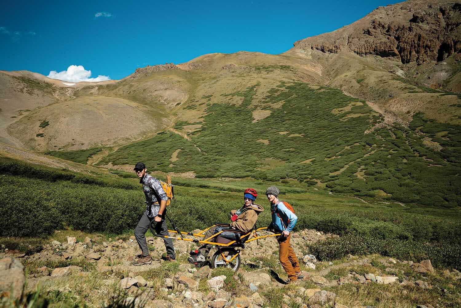 Three men traversing rugged terrain