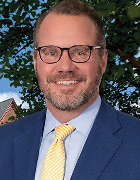 Man in glasses and yellow and white striped tie