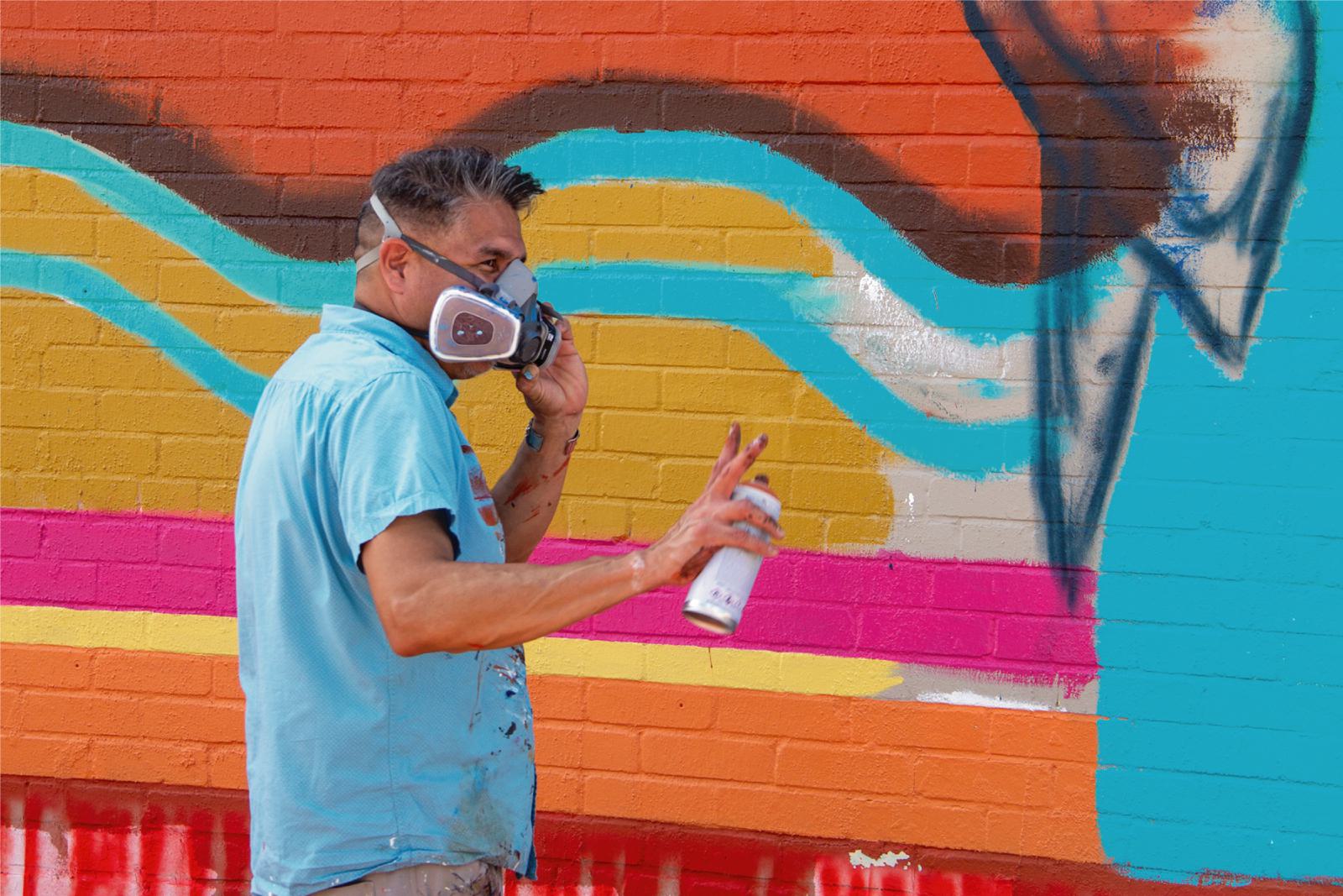 Man looking up from working on mural