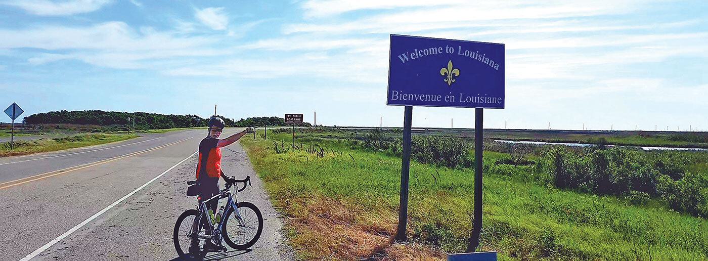 Man with bicycle near the Welcome to Louisiana sign